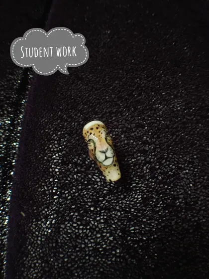 A student practicing detailed character work. This hand-painted leopard portrait on a single nail tip demonstrates precision and control with fine art brushes.