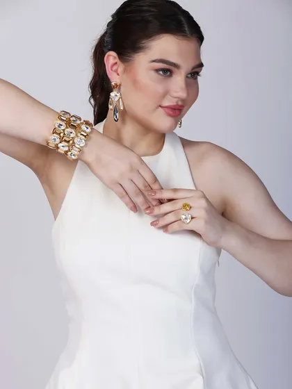 A dynamic pose where the model's hands frame her face, showcasing both a statement ring and a cuff bracelet. This composition is great for lifestyle shots that feel natural yet highlight the products beautifully.