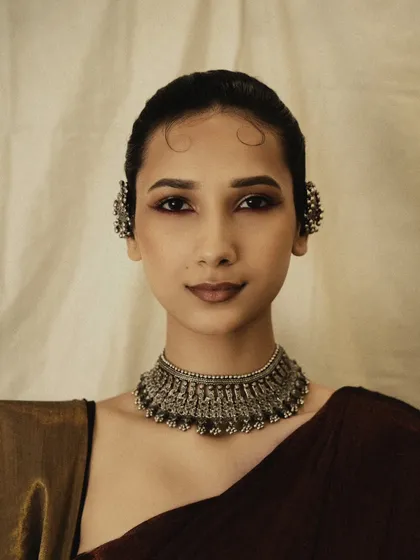 A clean, direct beauty shot focusing on the intricate silver choker and ear cuffs. The simple composition allows the craftsmanship of the jewelry to take center stage.