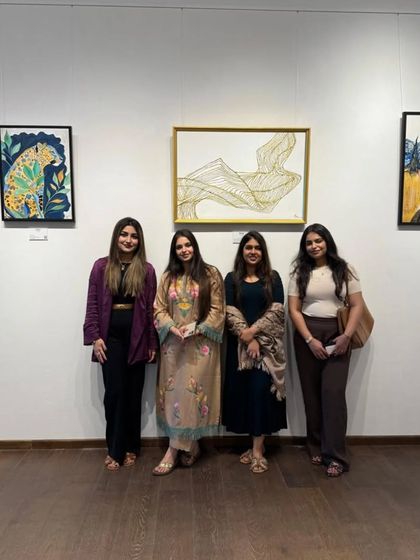 Artist Amya Singh and guests at the 'Ephemeral Dreams' exhibition, standing before a collection of her imaginative and colorful artworks.