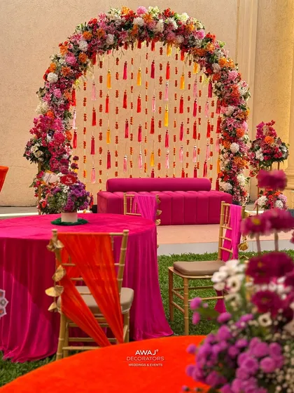 A view of the Mehendi seating from a guest table, showing the cohesive color scheme of pinks and oranges.