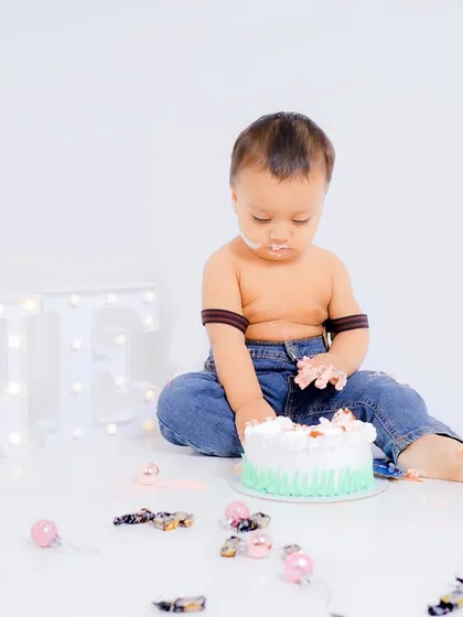 The moment before the fun begins. A portrait of the birthday boy with his first cake and the 'ONE' light-up prop in the background.