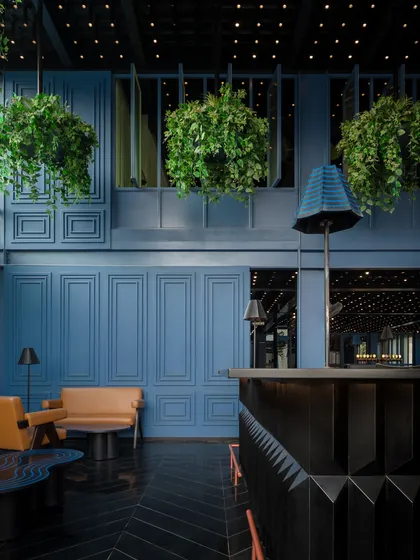 For this bar area, I created a cinematic, immersive mood using a deep blue palette on paneled walls and a faceted black granite bar. The design contrasts these cool, moody tones with the warmth of tan leather seating and a canopy of hanging plants, blending retro glamour with a touch of nature.