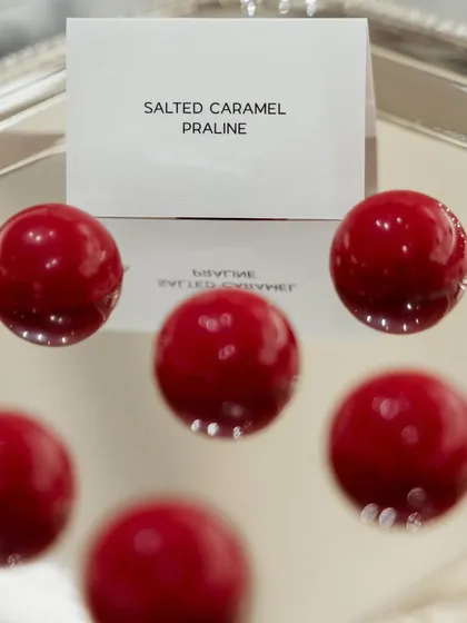 Glossy red salted caramel pralines, created for a Valentino event. The simple, bold, and elegant dessert echoes the brand's ethos of refined simplicity.