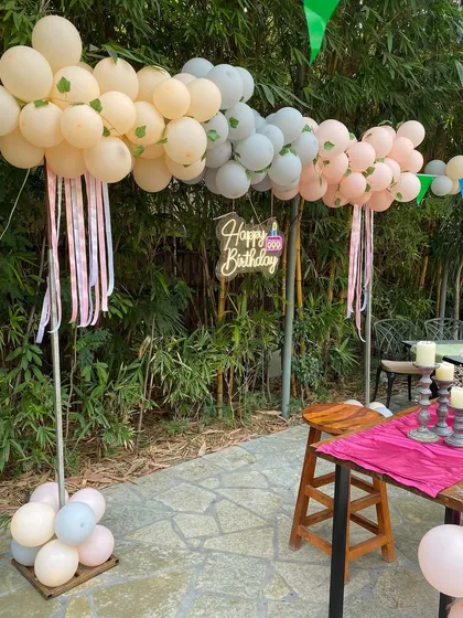 A beautiful pastel balloon setup for a birthday celebration in a garden restaurant.