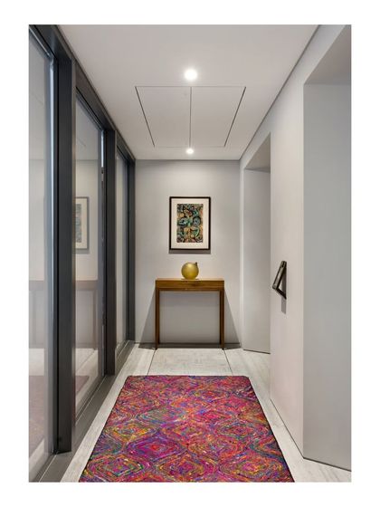 A colorful rug adds vibrancy to this passage in the Limestone Residence. Fluted glass doors are used to borrow light from adjacent rooms, brightening up the landlocked space.
