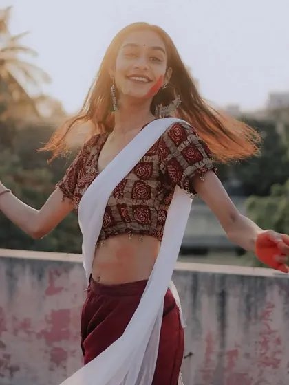 A candid shot of pure happiness, the model twirls with a wide smile, celebrating the festival of colors in her traditional attire.