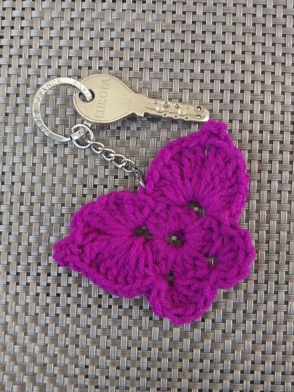 The butterfly keychain on a textured background, showing the open-stitch design of the wings.