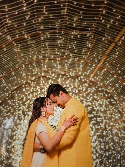 Surrounded by a tunnel of twinkling fairy lights, this couple shares an intimate moment. The warm yellow of their outfits and the magical glow of the lights create a stunning and romantic portrait.