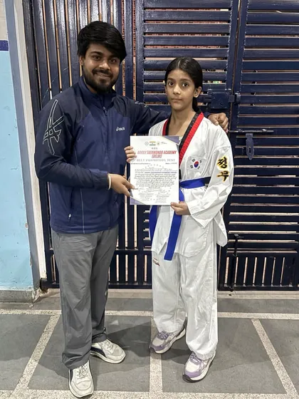This student proudly receives her blue belt certificate. Her progress shows what can be achieved with consistent training and a determined mindset.