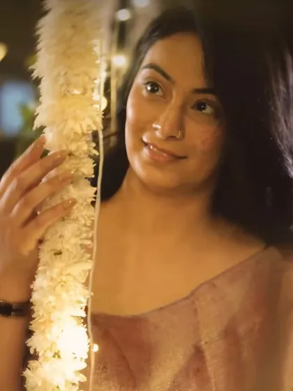 A guest enjoying the festive decor. The soft lighting and traditional floral elements provide a beautiful, candid photo opportunity during a cultural event.