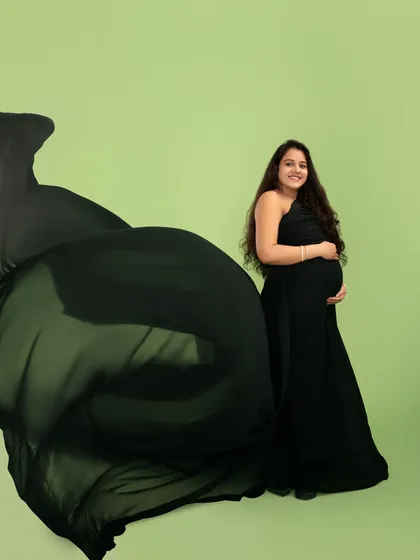 The classic black gown, elevated with a dramatic fabric toss. This technique adds movement and elegance, creating a timeless yet striking image that celebrates your changing form.