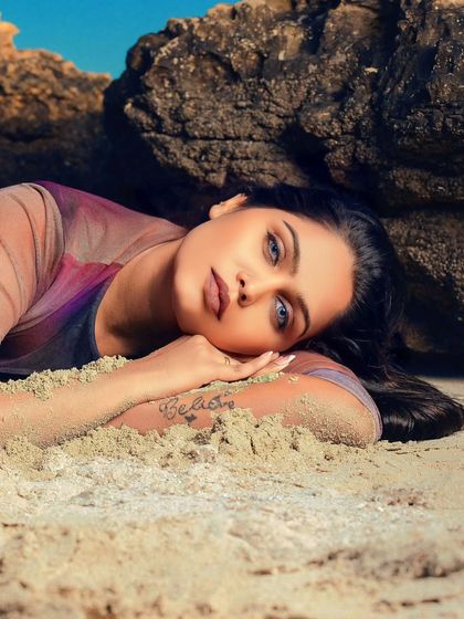 Found in the strength of the sand. A serene and beautiful portrait of a model resting on the beach, with her 'Believe' tattoo visible.