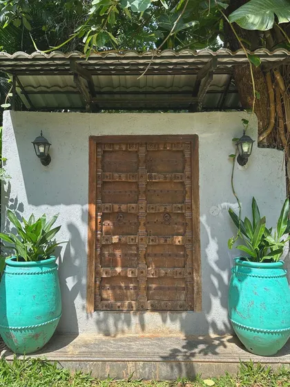 Make an entrance that tells a story. Our antique-finish terracotta 'Ubud' planters add a vibrant pop of turquoise, beautifully framing this rustic wooden door and creating an unforgettable welcome.
