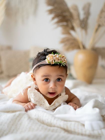 This is a classic shot from a 6-month session. The tummy time pose is perfect for showing off how strong they're getting, and her curious expression is just priceless.