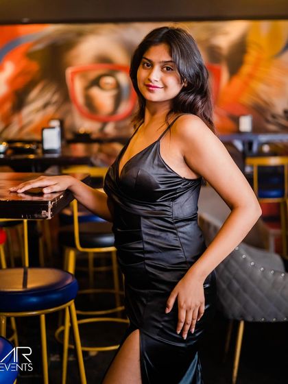 A guest in a black satin dress, posing against the graffiti wall.