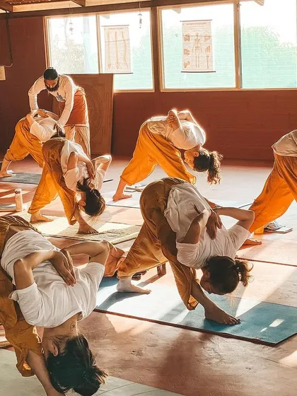 This is a duplicate of image 88. It showcases the dedication of our students as they move together in a challenging forward bend, with teachers providing support.