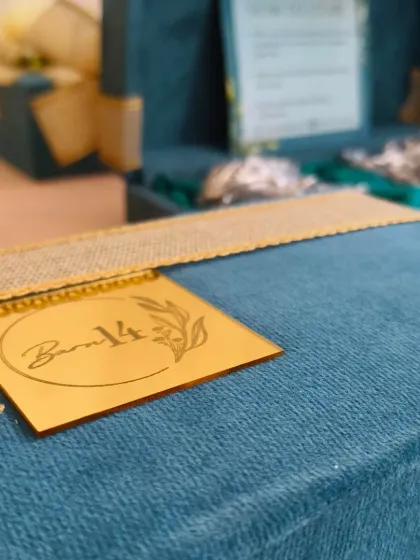 A detail shot focusing on the custom-engraved, gold-mirrored logo tag for 'Barn 14'. This level of detail in packaging helps to elevate a brand's identity.