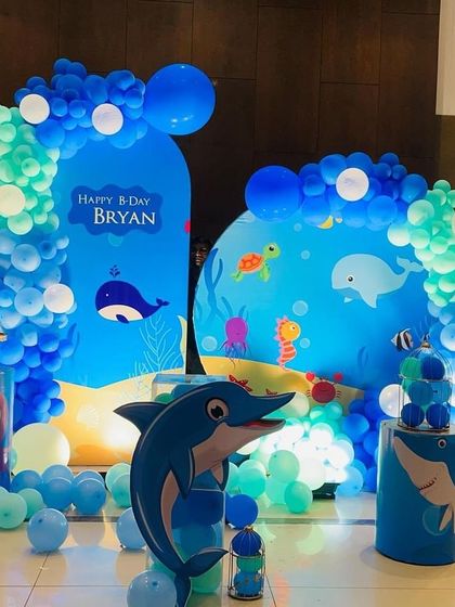 An underwater adventure with this Baby Shark and ocean life theme. The setup features multiple backdrops, character cutouts, and balloon arrangements in shades of blue and green.