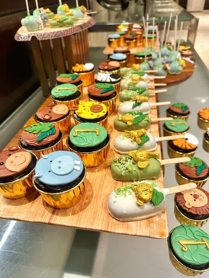 Every treat on the table contributes to the story. The cupcakes feature different animal faces and leaf designs, while the cakesicles are decorated with golden animals and green sprinkles for a touch of jungle magic.
