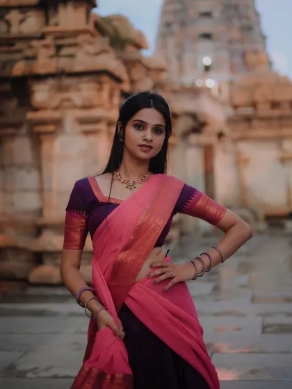 A striking portrait of a dancer against the backdrop of a historic temple. The composition balances the model's pose with the architectural details of the setting.