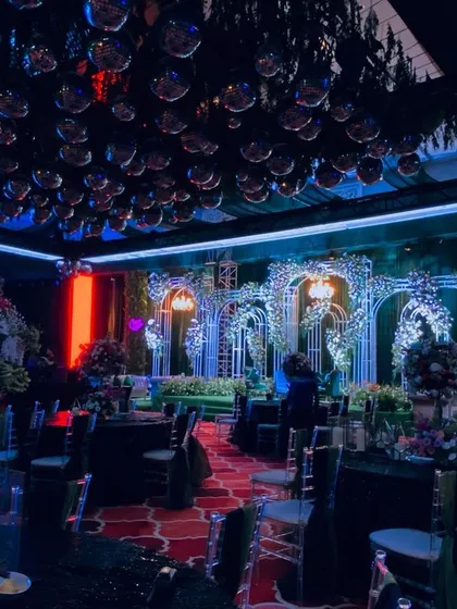 Time for the party. This sangeet night was all about high energy, with a ceiling full of disco balls, dramatic blue and red lighting, and elaborate floral arches, setting the stage for an unforgettable night of dancing.