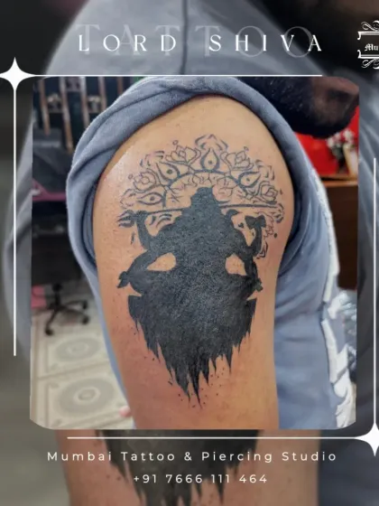 A powerful silhouette of Lord Shiva in his Tandava pose, set against a mandala. This bold, blackwork tattoo on the shoulder is a striking tribute to the divine destroyer and creator.