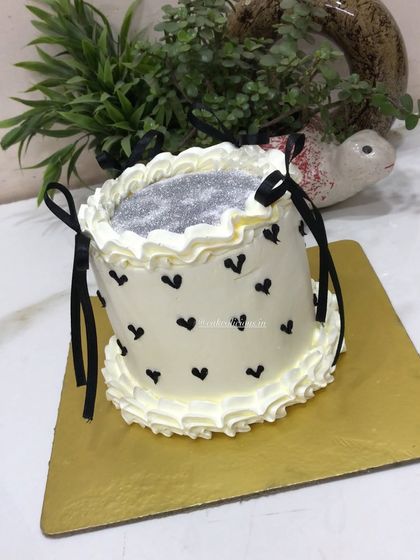 A chic glitter cake with black hearts and delicate black ribbon bows. This design is simple, modern, and perfect for a stylish birthday or bachelorette party.