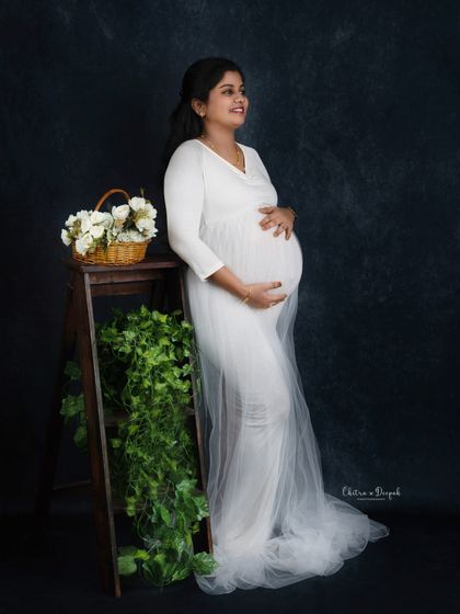 A serene and classic portrait. The mom-to-be in a simple white gown looks angelic, with rustic props adding a touch of warmth.