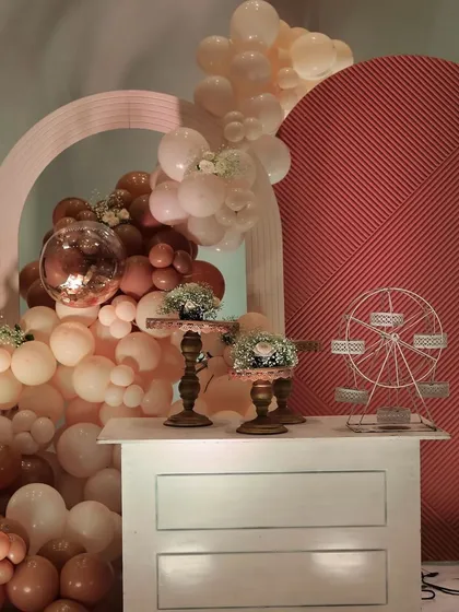 A closer look at the dessert station, featuring a miniature ferris wheel and cake stands, framed by a beautiful balloon arrangement and textured backdrops. Every corner is designed to be picture-perfect.
