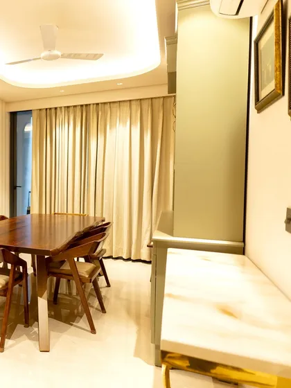 A closer look at the dining space, where the sleek lines of the live-edge table meet the soft curves of the ceiling cove lighting. The combination of natural wood, soft drapery, and marble accents creates a serene and luxurious ambiance.