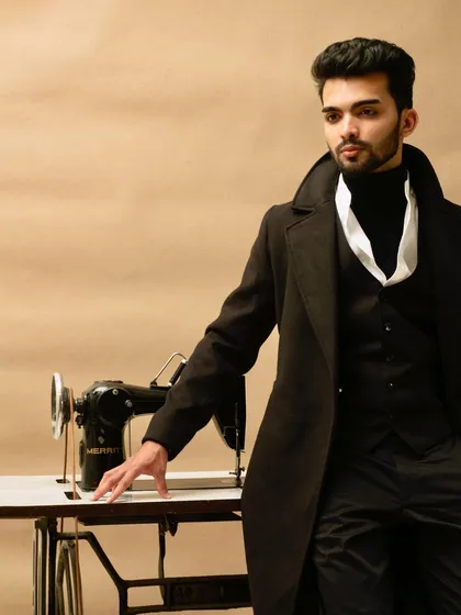 Inspired by period dramas, this shot combines classic tailoring with a dramatic pose. The three-piece suit and overcoat, set against a vintage sewing machine, create a thematic portrait that showcases a model's ability to embody a specific character and era.