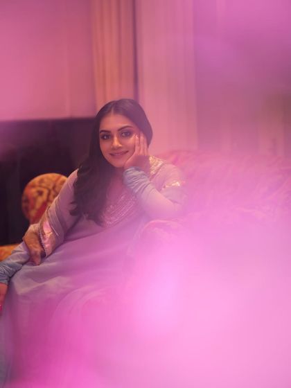 A dreamy and artistic portrait with a soft pink flare in the foreground. This creative shot adds a touch of magic to the traditional ethnic look.
