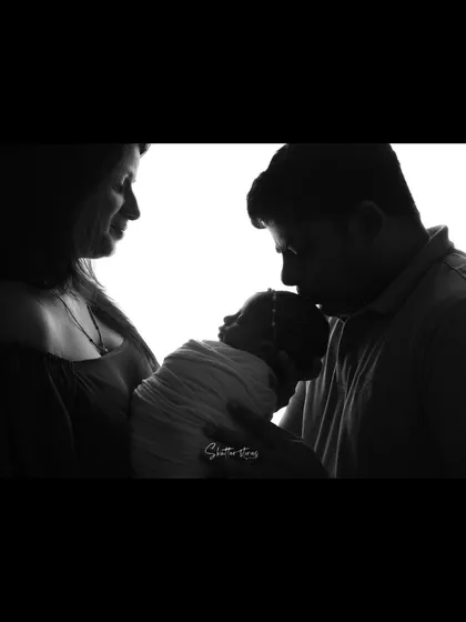 A tender moment captured in silhouette, with the father kissing the baby's head.