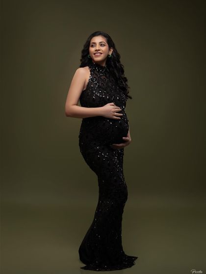 A full-length view of the black sequined gown, showing its elegant silhouette. This is a perfect choice for a timeless and sophisticated maternity look.