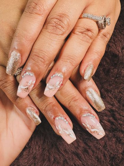 An elegant and sparkly design. This set features coffin-shaped nails with a mix of full-coverage gold glitter and abstract white and glitter art.