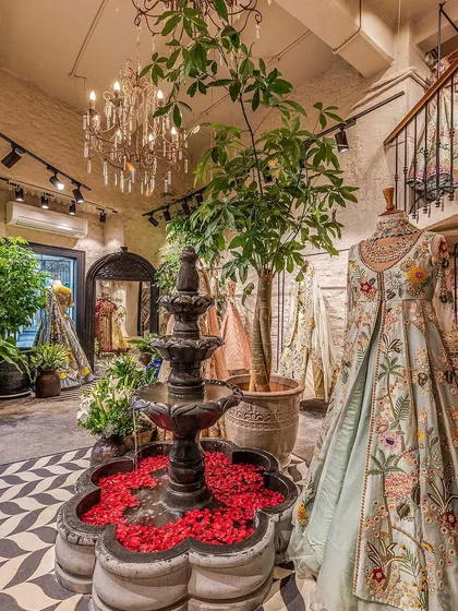 Welcome to The Vintage Garden. The centerpiece of our design is a black stone water fountain, creating an immediate sense of tranquility. We designed the entire retail space around creating an oasis-like experience, using vintage chandeliers, lush greenery, and a striking chevron floor to guide customers through the boutique.