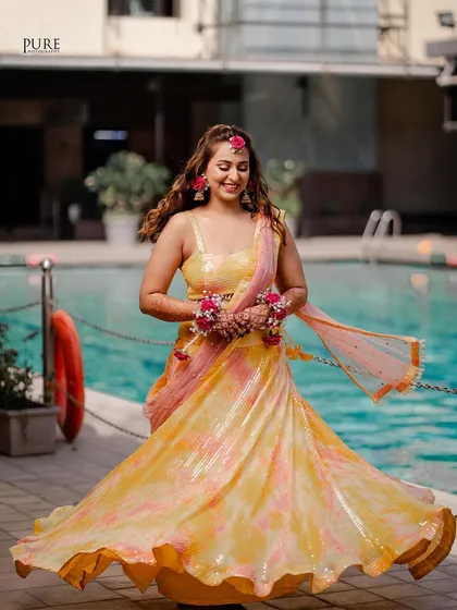 The bride twirling in her stunning yellow and pink lehenga at her poolside Haldi ceremony. A picture of pure joy and celebration.