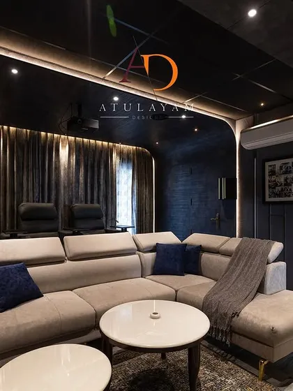 Another view of the home theatre, showing the dark, moody color palette and curved wall design that minimizes light reflection and enhances the viewing experience.