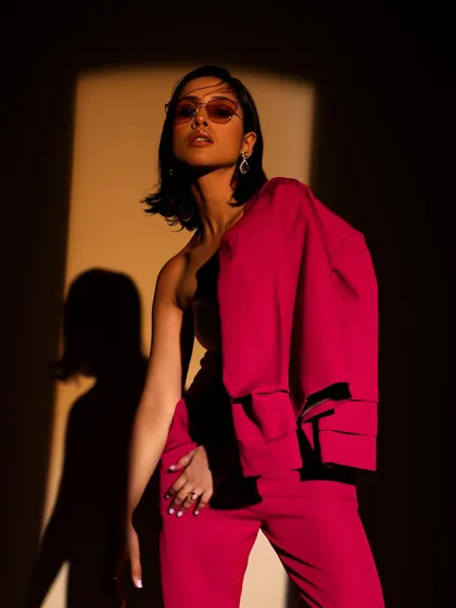 An alternative way to style a pantsuit, with the jacket draped over one shoulder. This approach adds a touch of effortless cool to a formal look, perfect for a fashion-forward brand.