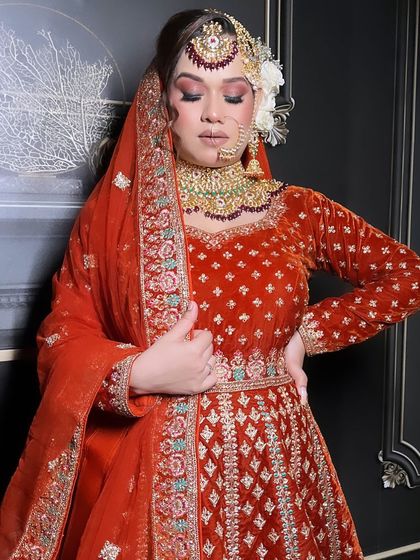 Another angle of the red-orange velvet bridal anarkali, showing how the rich fabric drapes. The full sleeves are finished with detailed embroidery at the cuff, ensuring every part of the outfit feels special.