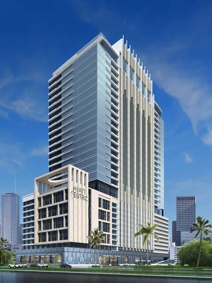 A design render for the Hyatt Centric in Mahape, viewed from across the water. The tower's design features strong vertical elements and a sleek glass curtain wall, projecting an image of modern corporate sophistication.