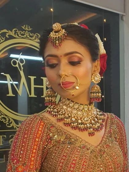A close-up of another one of my beautiful brides. This HD makeup look highlights her features with warm, shimmery eyeshadow, perfectly winged liner, and a soft pink lip, complemented by a traditional nath and maang tikka.