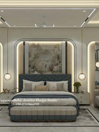 This grand master bedroom features a large, tufted blue headboard set within a beautifully lit arched frame. The design is luxurious, with a large piece of art and hanging globe lights completing the look.