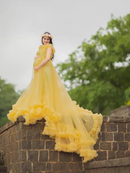 A majestic pose on a stone wall, with the long train of the yellow gown cascading down.