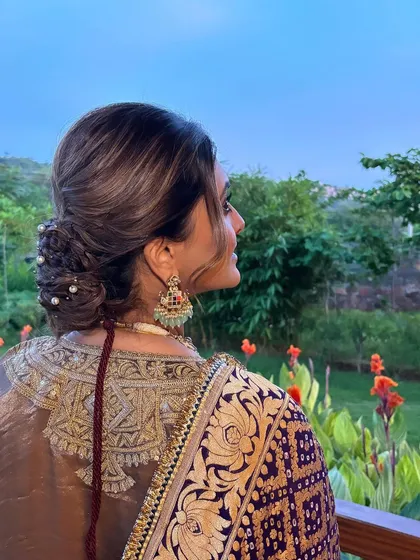A beautiful shot of a textured low bun with pearl accents, set against a scenic natural background. This hairstyle is perfect for an outdoor or destination wedding.
