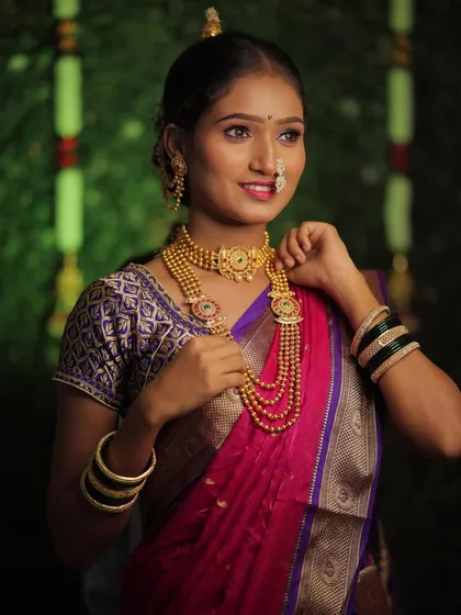 Another angle of this beautiful bride, showing her adjusting her jewelry. The focus is on the rich texture of the Paithani saree and the detailed gold jewelry that is central to the look.