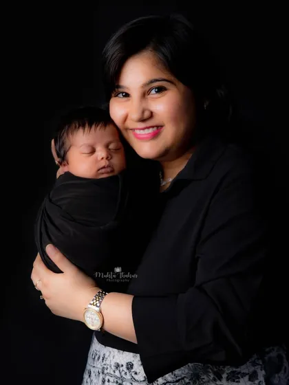 A mother's gentle love, captured in a simple, elegant portrait as she holds her sleeping newborn close.