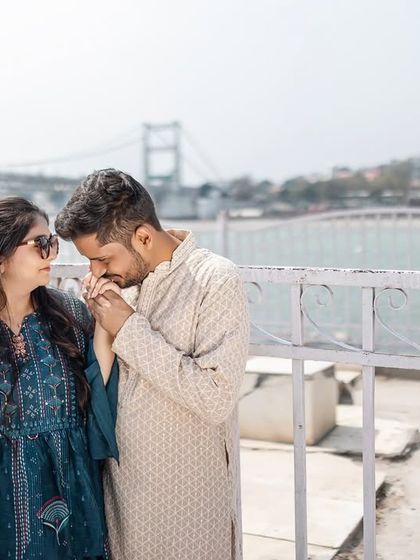 A tender moment on the ghat, with him kissing her hand. The Ram Jhula bridge in the background firmly places this beautiful pre-wedding shoot in Rishikesh.