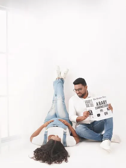 A playful pose for a pregnancy announcement. Using a custom sign adds a personal touch and shares the exciting news in a creative way.